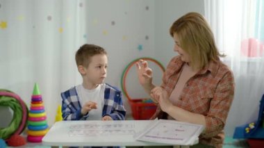 Kafkasyalı otistik anaokulu çocuğu bir konuşma terapistiyle çalışıyor. Bir çocuğu telaffuz ve harflerin doğru telaffuzu konusunda profesyonel olarak eğitmek. Yüksek kalite 4k görüntü