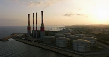 Gün batımında Kıbrıs 'ta deniz kenarında havadan izlenen elektrik santrali. Elektrik üretimiyle atmosfer ve denizin kirlenmesi. Yüksek kalite 4k görüntü