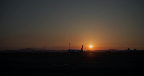 日落时的机场生活 飞机将飞往跑道 美丽的城市景观与橙色的天空 高质量的4K镜头 — 图库视频影像