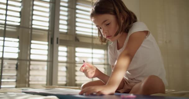 Χαρούμενο Κοριτσάκι Που Γράφει Σημειωματάριο Στο Κρεβάτι Ένα Παιδί Μαθαίνει — Αρχείο Βίντεο