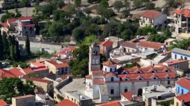 Lefkara Kıbrıs şehir manzarasının havadan görüntüsü. Tarihi şehrin merkezinde çan kulesi olan bir kilise. Kırmızı çatıları olan güzel bir mimari manzara. Yüksek kalite 4k görüntü