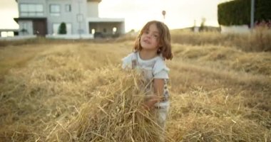 Neşeli bir Kafkasyalı kız samanlıkta samanlıkta oynuyor, saçıyor. Mutlu bir çocukluk ve çiftlikte mutlu. Yüksek kalite 4k görüntü