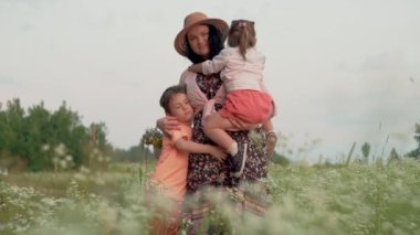 Aile Bağlarının Büyüsü: Mutlu bir Avrupalı Anne, Kız ve Oğlanın Unutulmaz Anlarını Büyüleyici Günbatımında Sallanan Çimenler 'de Anlatırken Çekmek. 