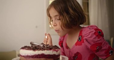  Pastanın üzerinde mum ışığını yanlışlıkla bırakan bir çocuğun büyüleyici bir doğum günü gafı görüntüsü. Yüksek kalite 4k görüntü