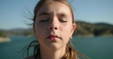Gözlerini kapatmış ve meditasyon yapan genç bir kızın yüzünü yakından çek. Çocuk stresten kurtulup yalnız başına dinlenmek istiyor. Yüksek kalite 4k görüntü