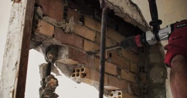 Building Breakthrough: Detailed Shot of Mans Hands Using a Rotary Hammer to Demolish a Wall, Illustrating Construction and Labor. High quality 4k footage