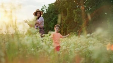Happy smiling mother and son dancing together in field at sunset. Smiles of the family time spent together in the movements of the dance. High quality 4k footage