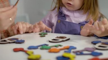 The girl learns colors with the teacher in the kindergarten while playing the game. The child chooses the correct puzzle that matches the color, logical development games. High quality 4k footage