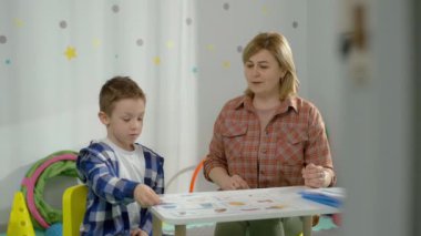 Bir çocuk, bir oğlan, bir öğretmenle birlikte bir anaokulunda okuyor. Çocuk mantık görevleri yapıyor. Akıllı çocuklar mutlu çocukluk kavramı. Yüksek kalite 4k görüntü