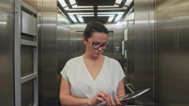 Şirkete Dönüş: İş kadını Tablet ve Belgeleri Ofis Merkezi Asansöründe, Bir İş Merkezi Randevusu 'na Gidiyor. Yüksek kalite 4k görüntü
