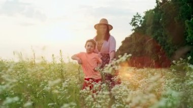 Anne ve oğlunun gün batımında bir tarlada ritmik bir şekilde dans ettiği komik bir video. Mutlu aile gülümseyen çocuklar birlikte müzik zamanı geçiriyorlar. Yüksek kalite 4k görüntü