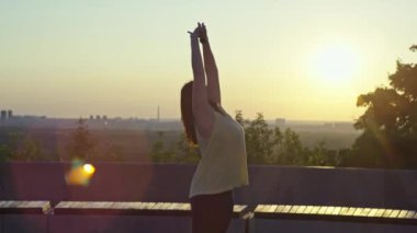 Güzel bir kız şafakta şehirde sabah egzersizi yapar. Bir kadın parkta egzersiz yapar ve esneme hareketleri yapar. Yüksek kalite 4k görüntü