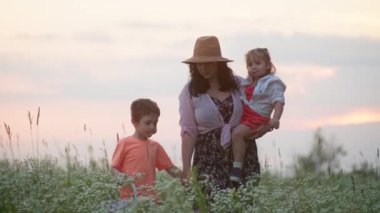 Aile Mutluluğunun Yolu 'nun Aydınlanması: Parlak Çocukluk kavramını sembolize eden, Sevilen Avrupalı Anne, Kız ve Oğlu Güneş Işığı Alanının Huzurlu Ortasında Huzurlu Gezintiyi Paylaşıyorlar.
