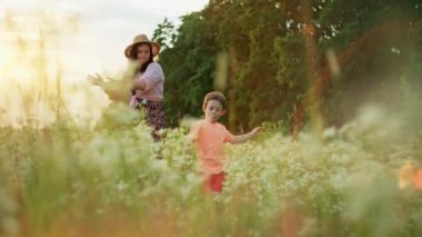 Happy smiling mother and son dancing together in field at sunset. Smiles of the family time spent together in the movements of the dance. High quality 4k footage