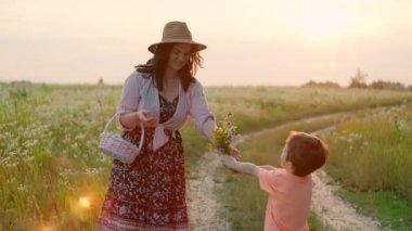 The son gives flowers to his mother in the field. Happy family together love of child to parents. Concept of tenderness of happiness and smiles. High quality 4k footage