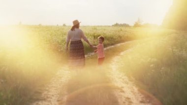 Bir anne köy yolunda yürürken oğluyla el ele yürür. Mutlu ebeveyn sevgisi mutluluk ve özgürlük kavramı. Yüksek kalite 4k görüntü