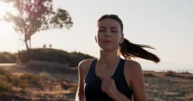 Atletik beyaz bir kızın koşu portresi. Fitness sağlıklı yaşam tarzı güzel bir kadın gün batımında koşuyor ve spor yapıyor. Yüksek kalite 4k görüntü