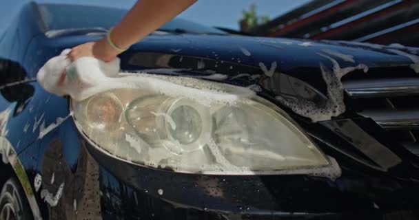 女性のクローズアップ フォームウォッシュクロスで車のヘッドライトを洗う手 高品質の4K映像 — ストック動画