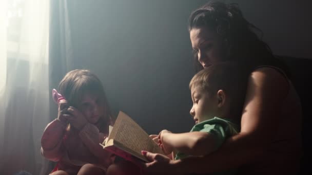 Μητέρα Διαβάζει Ένα Παραμύθι Στα Παιδιά Που Κάθονται Στο Πάτωμα — Αρχείο Βίντεο