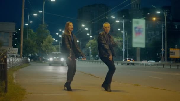 美丽的男女青年在城市街道上跳高跟鞋舞 舞动伴随着夜城音乐的节拍与城市景观 高质量的4K镜头 — 图库视频影像