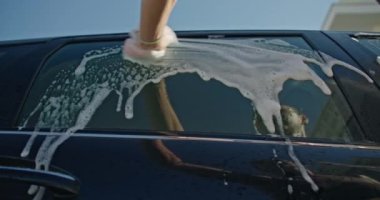 Araba yıkamak için köpüğü havluyla ovuşturan bir kadının yakın çekimi. Yolculuk için arabayı temizliyorum. Yüksek kalite 4k görüntü