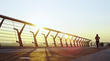 Gün doğumunda spor takım elbiseli bir kızın olduğu şehirde sabah koşusu. Şehir manzarasında koşmak ve spor yapmak çok yorucu. Yüksek kalite 4k görüntü