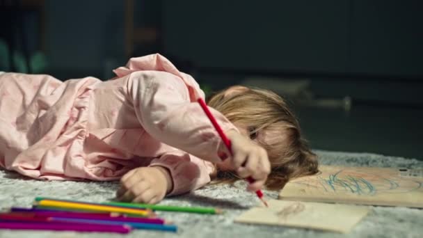 コーカサス人の女の子は床に横たわっている間に紙に鉛筆で描きます 絵画の芸術を学ぶ美しい子供の肖像画 高品質の4K映像 — ストック動画