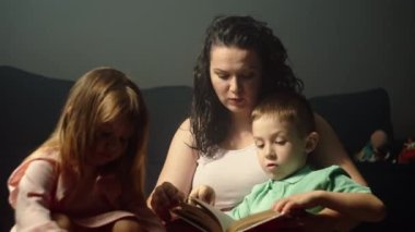 Annem çocuklar için bir masal kitabı okuyor. Çocuklu mutlu bir aile birlikte vakit geçirir. Ebeveynlerin çocuklara duyduğu sevgi ve ilgi. Yüksek kalite 4k görüntü