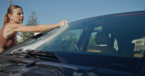 女性は発泡布で車の窓を洗います 庭の家の汚れから車を掃除する 高品質の4K映像 — ストック動画