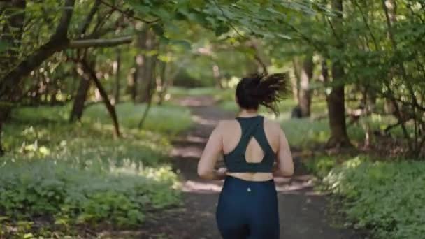 美しい太りすぎとサイズの女の子が森の中を走っています 体重減少のための運動とフィットネス アクティブなライフスタイルを持つ女性 高品質の4K映像 — ストック動画