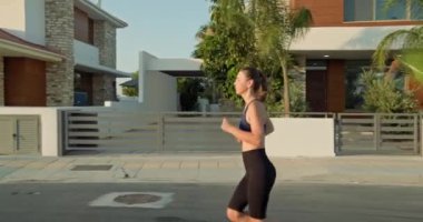 Sabah koşusu yapan bir kadın köy caddesinde koşuyor. Sporcu, sporcu, hayat tarzıyla yolda koşan bir kadın. Yüksek kalite 4k görüntü