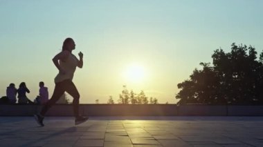 Gün doğumunda koşan güzel şişman kadın. Spor yapan ve kilo vermek için diyet yapan bir kızın silueti. Sağlıklı bir yaşam tarzı. Yüksek kalite 4k görüntü