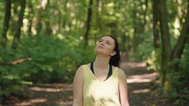 在试听了耳机里的音乐后 分等级的女孩在森林里走来走去 积极的生活方式 自由和自然 高质量的4K镜头 — 图库视频影像