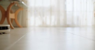 Robot elektrikli süpürge yerde seyahat ederken çalışıyor ve odayı süpürüyor. Akıllı ev, ev temizlik ekipmanları. Yüksek kalite 4k görüntü