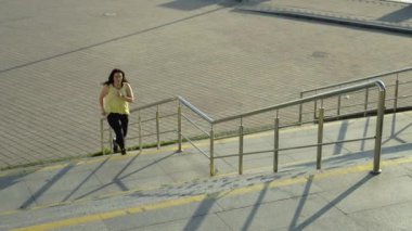 Sabah koşusu yapan bir kız merdivenlerden yukarı koşar. Şehirdeki spor ve spor sahaları. Yüksek kalite 4k görüntü