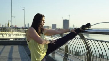 Beyaz kadın şehir manzarasında koşmadan önce ısınıyor. Güzel bir kızın esneme hareketleri için spor yaşam tarzı ve aktif bir spor hayatı. Yüksek kalite 4k görüntü