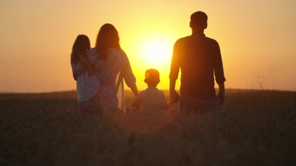 おとぎ話の家族のシルエットと子供たちは日没に小麦畑を歩いています 一緒に幸せな家族のコンセプト 笑顔と親の愛 高品質の4K映像 — ストック動画