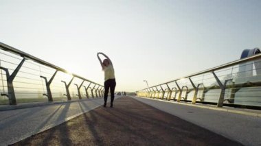 Yeni Gün, Yeni Bir Koşu: Kadın Gün doğumunda Şehir Koşusu 'ndan önce Sabah Isınma Ritüeli uyguluyor. Yüksek kalite 4k görüntü
