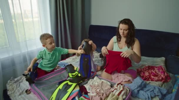 Glückliche Kinder Packen Mit Ihrer Mutter Kleidung Einen Koffer Für — Stockvideo