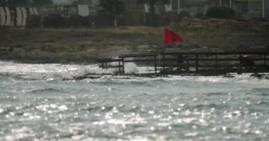 Deniz kenarındaki sahilde kırmızı bayrak. Fırtına ve yüksek dalgalar yüzmeyi yasaklıyor. Yüksek kalite 4k görüntü