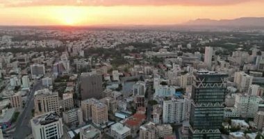 Kıbrıs Rum Kesimi 'nin Lefkoşe kentinin havadan görünüşü. Şehir merkezinde iş merkezleri ve gökdelenleri olan bir şehir manzarasında gün batımı. Yüksek kalite 4k görüntü