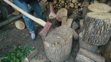 Yakın plan bir adam kütüğe kütük koyar ve baltayla doğrar. Çiftlikteki kış için şömine için odun topluyorum. Yüksek kalite 4k görüntü