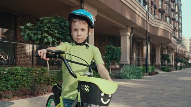 街並みのヘルメットで自転車に乗った子供の男の子の肖像 楽しい アクティブな子供時代 そして外で遊びます 高品質の4K映像 — ストック動画