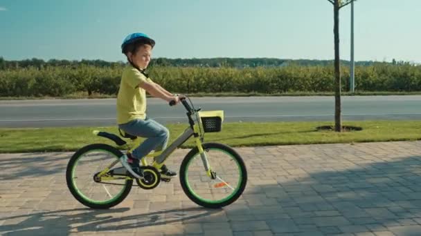 一个孩子 一个男孩 在城市的一条自行车道上骑着一辆汽车 那孩子正高兴地骑着自行车 面带微笑 高质量的4K镜头 — 图库视频影像