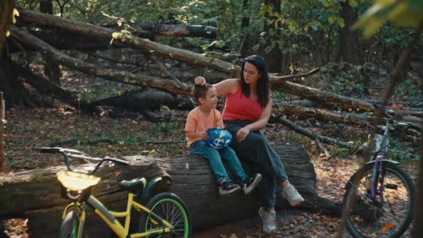 母と息子は森で自転車に乗っている間に木の上に座っている 自然の中で家族と過ごす時間は 幸せと笑顔のアクティブなライフスタイルです 高品質の4K映像 — ストック動画