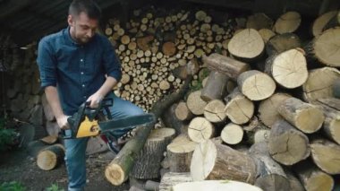 Adamın biri yakacak odun için elektrikli testereyle ağaç kesiyor. Köydeki bir çiftlikte yakacak odun toplamak zor iş. Yüksek kalite 4k görüntü