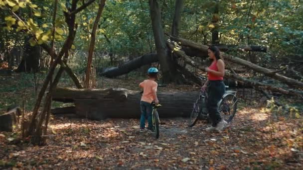 喜びと共生の日 ママと息子は公園で自分自身を浸し ハーモニーでバイクをしています 高品質の4K映像 — ストック動画