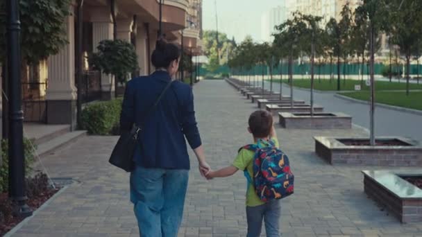 一位母亲带着背包带着她的儿子沿着城市街道上学 一个快乐的孩子 他的父母带他去上课 高质量的4K镜头 — 图库视频影像
