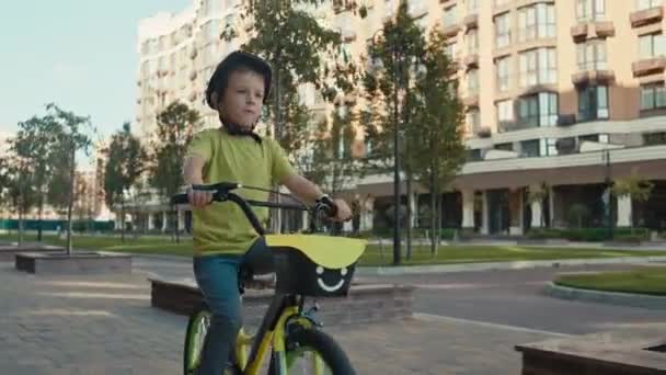 Egy Fiú Biciklizik Városban Egy Bukósisakos Aktív Gyerek Biciklizik Városképben — Stock videók