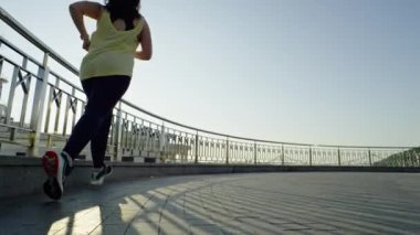 Şehirde formları ve kiloları olan güzel bir kadın sabah koşusunda. Kız kilo vermek için spor yapıyor ve koşuyor. Vücut bakımı ve diyet. Yüksek kalite 4k görüntü